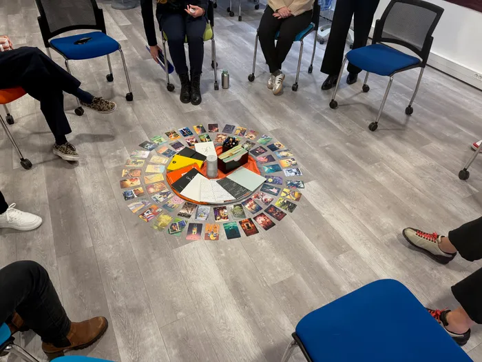 Cercle de chaises autour de cartes disposées au sol